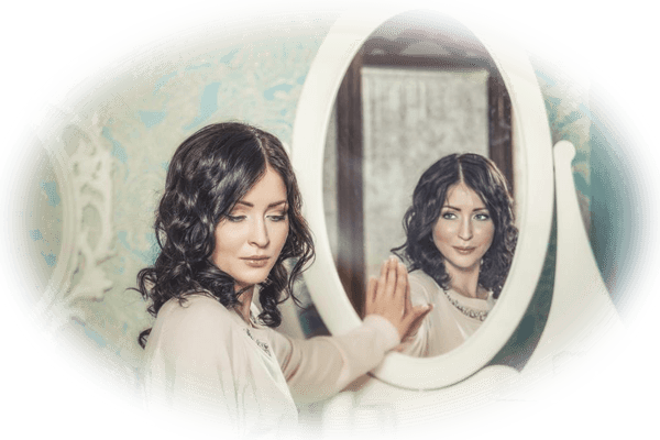 Woman looking away from a mirror while her reflection looks at her